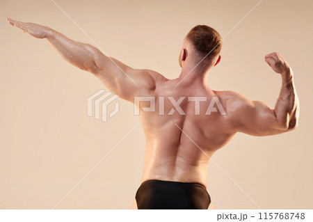 Medium shot of unrecognizable strong bodybuilder performing rear archer pose in studio on neutral background, copy space 115768748