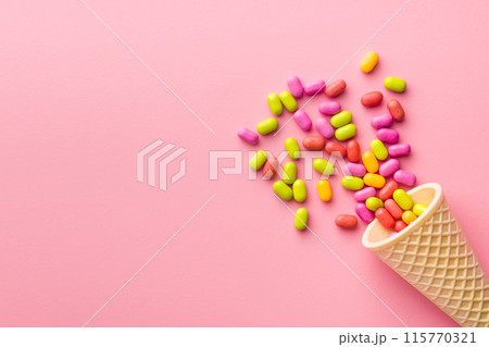 Colorful hard mint Candies in ice cream cone on pink background. Top view. Colorful hard mint Candies in ice cream cone on pink background. Top view. 115770321