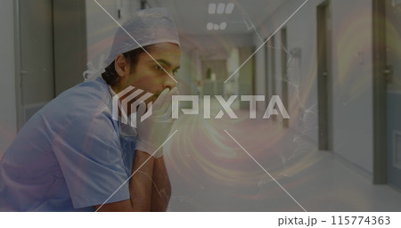 Image of moving spiral over sad biracial male nurse in hospital 115774363