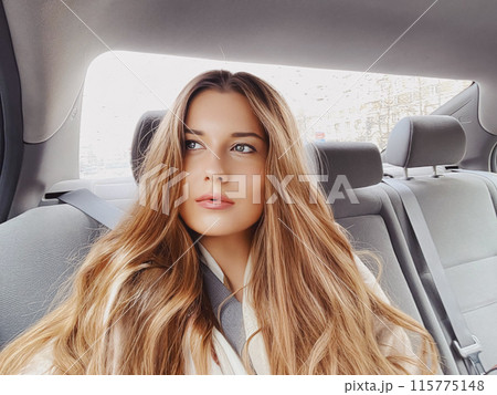 Young woman with long hair, wavy hairstyle in the car or taxi cab as passenger, exploring the city, transport and travel idea Young woman with long hair, wavy hairstyle in the car or taxi cab as passenger, exploring the city, transport and travel idea 115775148