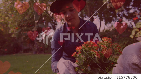 Image of heart emojis over caucasian woman gardening 115776300