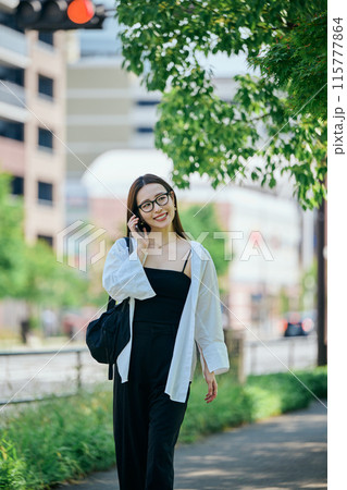 スマホで電話しながら歩く若い女性 115777864
