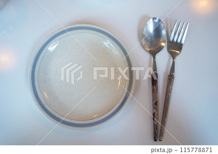 Empty plate with spoon and fork on white table. Top view. Empty plate with spoon and fork on white table. Top view. 115778871