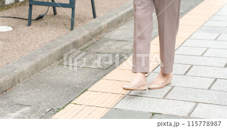 街を歩くビジネスウーマンの足元（点字ブロック・視覚障害者） 115778987