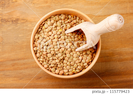 Brown raw dry lentils in wooden bowl on rustic wood table 115779423