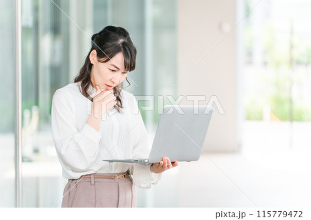 ノートパソコンを見ながら困る・考えるアジア人ビジネスウーマン（トラブル・書き込み・口コミ・低評価） 115779472