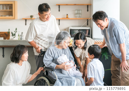 赤ちゃんと対面する車椅子に乗った高齢者女性と子供達・家族 115779891