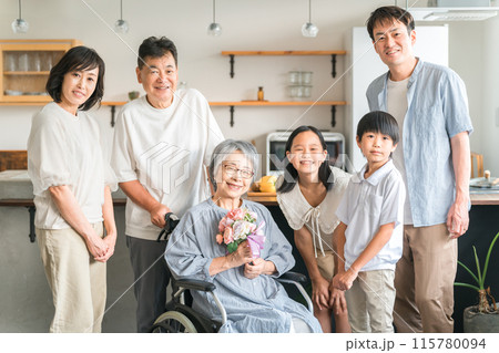 敬老の日・花束を持つ車椅子に座った高齢者女性と三世代家族 敬老の日・花束を持つ車椅子に座った高齢者女性と三世代家族 115780094