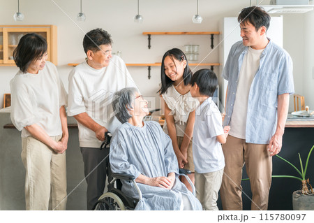 車椅子に座った高齢者女性と三世代家族 115780097
