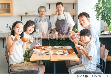 家のダイニングで家族団欒して食事する子供と夫婦・親子・三世代家族（二世帯住宅） 115781984