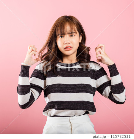 Asian happy portrait beautiful cute young woman standing angry and mad raising fist frustrated and furious while shouting with anger isolated, studio shot on pink background and copy space 115782531