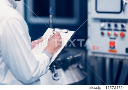 Scientist Medical Factory Staff Working in Science Lab. Medicine factory Technician Employee Check Care Products Quality in Sterilize Room Taking Note in Check list. 115785724