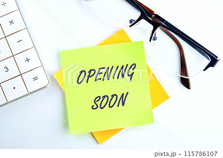 The words Opening soon text the inscription on the sticker on a light background next to the clock and calculator 115786107
