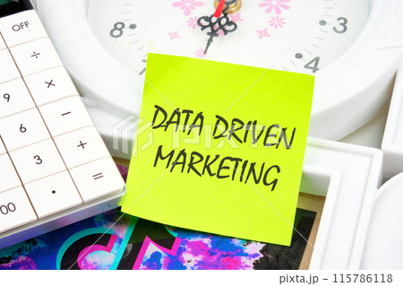 Business concept. Data driven marketing inscription on a yellow sticker on the background of the clock Business concept. Data driven marketing inscription on a yellow sticker on the background of the clock 115786118