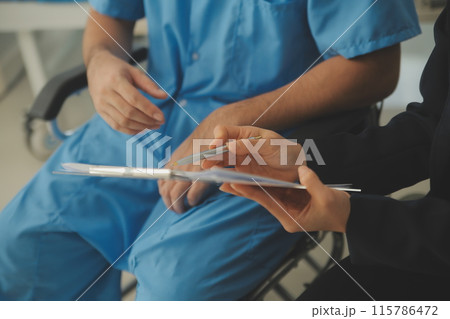 Midsection of female nurse checking blood pressure of woman sitting on wheelchair in clinic 115786472