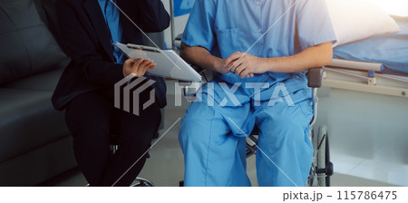 Midsection of female nurse checking blood pressure of woman sitting on wheelchair in clinic 115786475