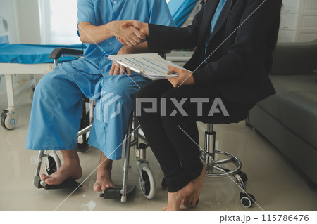Midsection of female nurse checking blood pressure of woman sitting on wheelchair in clinic 115786476