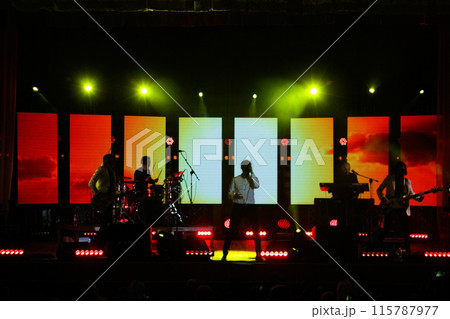 Music band on the stage. Concert stage performance, live band show. Dynamic music event with musician silhouettes. Black and red stage lighting background Music band on the stage. Concert stage performance, live band show. Dynamic music event with musician silhouettes. Black and red stage lighting background 115787977