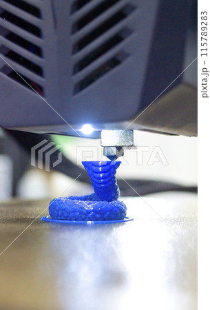 3D printer close up. A working 3D printer in process of printing object from molten plastic. 3D printer creating model by flowing liquid plastic from an extruder of printer. 3D printing technology 115789283