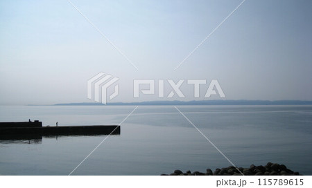 青空と凪の日本海と佐渡ヶ島と防波堤の釣り人 青空と凪の日本海と佐渡ヶ島と防波堤の釣り人 115789615