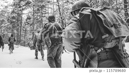 Heroes Of War. Re-enactors Dressed As American Infantry Soldier Marching Through Forest Road In Cold Winter Day. Group Of Usa Soldiers Marching Country Road. Usa Army Soldiers Of World War Ii 115789680