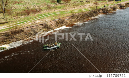 Men Dressed As US American Soldiers Of USA Infantry Of World War II carry out rafting on rubber boats In spring Autumn Day. Group of Soldiers people are preparing to disembark. Aerial view elevated Men Dressed As US American Soldiers Of USA Infantry Of World War II carry out rafting on rubber boats In spring Autumn Day. Group of Soldiers people are preparing to disembark. Aerial view elevated 115789721