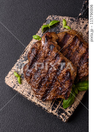 Fresh juicy delicious beef steak on a dark background Fresh juicy delicious beef steak on a dark background 115790806