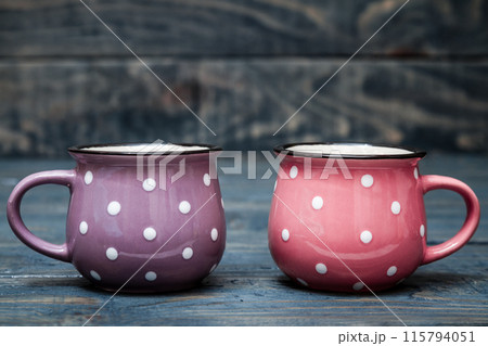 Pink and Purple Ceramic Mugs with White Dots on Blue Wooden Background Pink and Purple Ceramic Mugs with White Dots on Blue Wooden Background 115794051