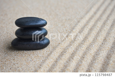 Black zen stones with lines carved on sand background. Black zen stones with lines carved on sand background. 115798487