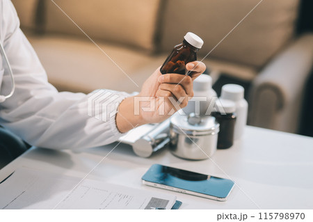 .Handsome young doctor with a beard and a lab coat taking of his glasses to read an email in his laptop .Handsome young doctor with a beard and a lab coat taking of his glasses to read an email in his laptop 115798970
