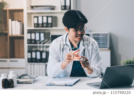 A dentist is using specialized dental equipment to inspect dentures to study the anatomy of the teeth before using the knowledge to treat patients, Dentures are being studied by oral specialists. 115799220