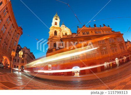 Tram is speeding along the streets of prague at twilight, passing by st. Nicholas church 115799313