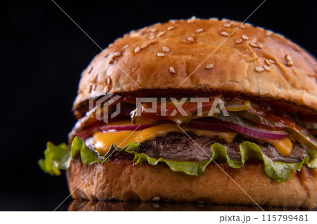 Burger with beef, cheese, vegetables on black plate. Dark Background. Close up. 115799481