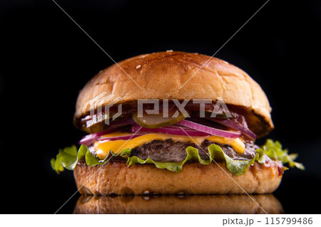 Burger with beef, cheese, vegetables on black plate. Dark Background. Close up. Burger with beef, cheese, vegetables on black plate. Dark Background. Close up. 115799486