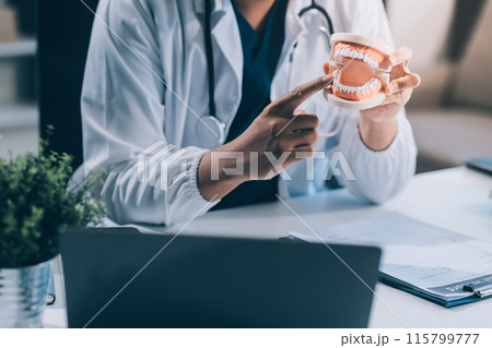 A dentist is using specialized dental equipment to inspect dentures to study the anatomy of the teeth before using the knowledge to treat patients, Dentures are being studied by oral specialists. 115799777