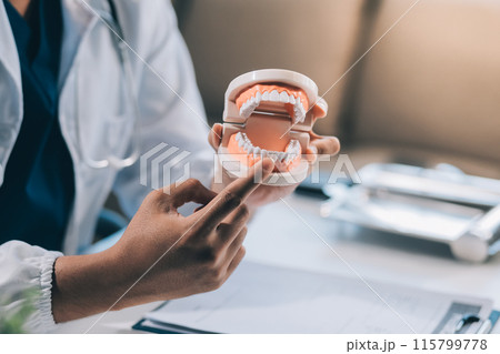 A dentist is using specialized dental equipment to inspect dentures to study the anatomy of the teeth before using the knowledge to treat patients, Dentures are being studied by oral specialists. A dentist is using specialized dental equipment to inspect dentures to study the anatomy of the teeth before using the knowledge to treat patients, Dentures are being studied by oral specialists. 115799778