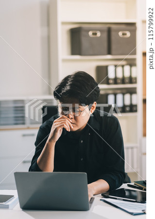 Frustrated Asian young businessman worker working on table in office. Busy employee worker people feel tired and headache from late work and overwork job document on computer desk at company workplace 115799922