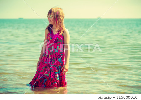 Little girl wearing dress playing in water 115800010