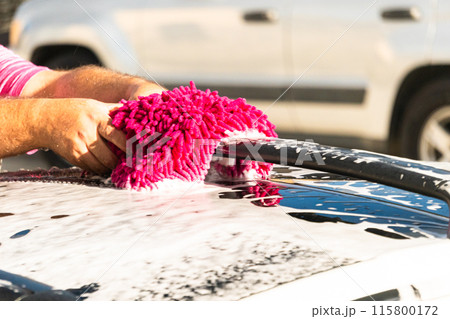 Efficiently cleaning an electric car in the comfort of a suburban driveway, combining eco-consciousness with practicality. Efficiently cleaning an electric car in the comfort of a suburban driveway, combining eco-consciousness with practicality. 115800172