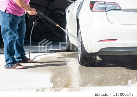 Efficiently cleaning an electric car in the comfort of a suburban driveway, combining eco-consciousness with practicality. Efficiently cleaning an electric car in the comfort of a suburban driveway, combining eco-consciousness with practicality. 115800178