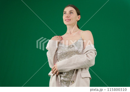 woman dances on green background chromakey woman in a beautiful Silver dress and jackets smiles opens the jacket shows beautiful teeth hair well-groomed dear girl 115800310