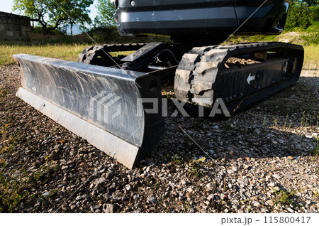 Bucket and rubber crawler tracks of a small excavator close-up Bucket and rubber crawler tracks of a small excavator close-up 115800417