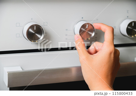Using an oven, close-up of oven temperature control. A woman's hand sets the temperature at the oven Using an oven, close-up of oven temperature control. A woman's hand sets the temperature at the oven 115800433