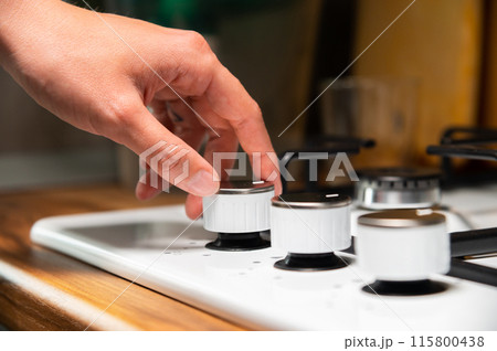 woman's hand turns on the gas stove. protection from children. Gas systems concept. Gas stove with electric ignition 115800438