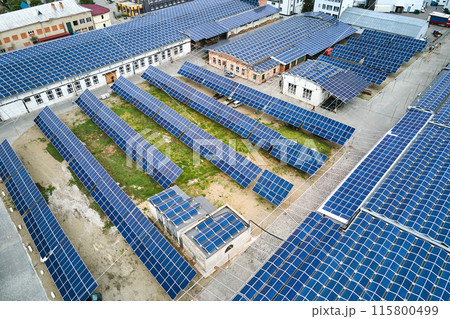 Aerial view of blue photovoltaic solar panels mounted on industrial building roof for producing green ecological electricity. Production of sustainable energy concept. 115800499