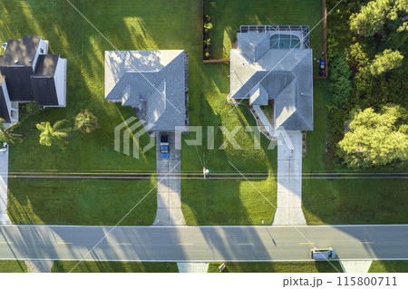 Aerial view of american small town in Florida with private homes between green palm trees and suburban streets in quiet residential area Aerial view of american small town in Florida with private homes between green palm trees and suburban streets in quiet residential area 115800711
