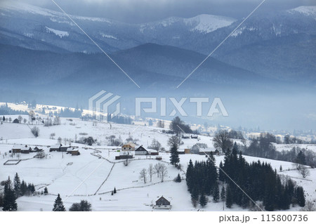 Winter landscape with small rural houses in remote settlement between snow covered forest in cold mountains Winter landscape with small rural houses in remote settlement between snow covered forest in cold mountains 115800736