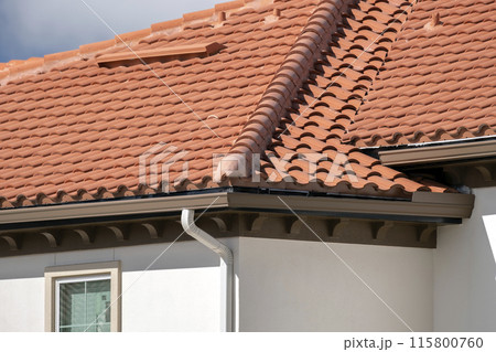 Closeup of house rooftop covered with ceramic shingles. Tiled covering of building Closeup of house rooftop covered with ceramic shingles. Tiled covering of building 115800760