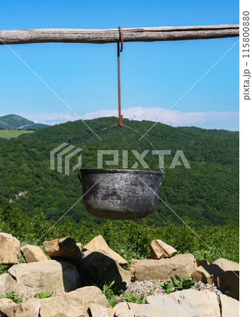 Metal pot hanging above fireplace in mountains 115800880