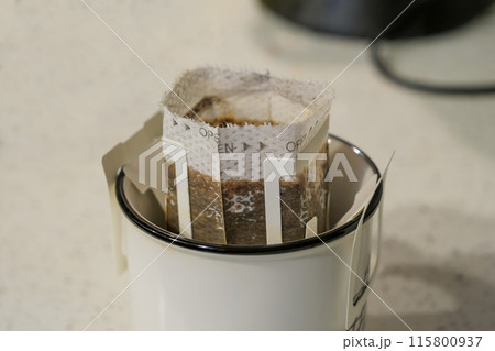 Drip filter coffee bag in ceramic cup close-up indoors daytime 115800937